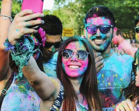 Group of people taking groufie with brightly coloured powder on their faces