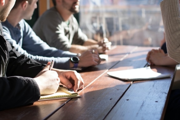 People with pens and notepads sitting round a table