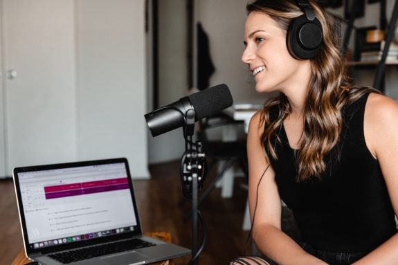 Woman sitting on chair in front of microphone and laptop